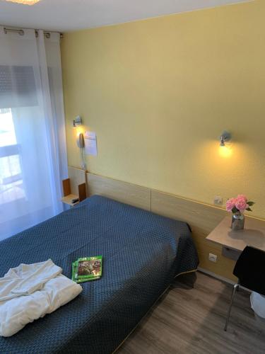 a bedroom with a bed with a book on it at Hotel Bains Sarrailh in Dax
