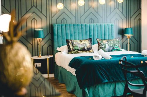 a bedroom with a bed with a blue headboard and pillows at Les Précieuses Suites & Spa I in Avignon