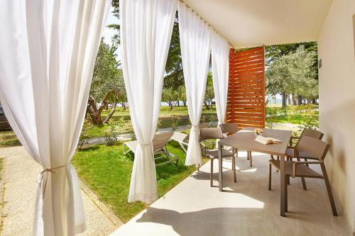 a patio with white curtains and a table and chairs at Adria Apartments - Hotel & Resort Adria Ankaran in Ankaran