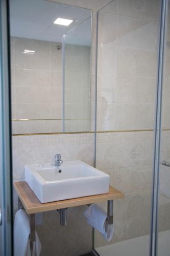 a bathroom with a sink and a glass shower at Tomás Guest House in Covilhã