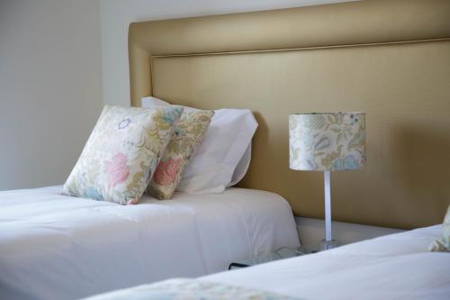 a hotel room with two beds and a lamp at Tomás Guest House in Covilhã