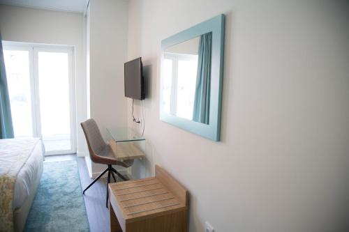een slaapkamer met een bed, een spiegel en een bureau bij Tomás Guest House in Covilhã