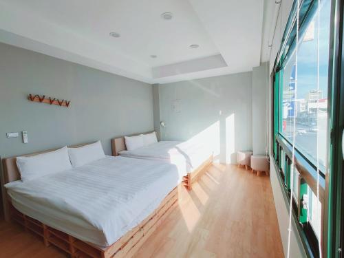 花蓮市にあるM Houseの大きな窓付きの客室で、ベッド2台が備わります。