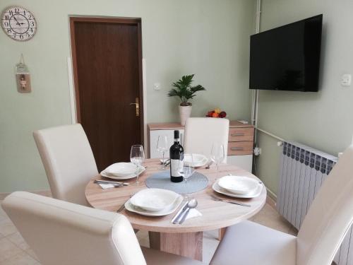 a dining room table with white chairs and a bottle of wine at Apartment Antea-Opatija Riviera in Mošćenička Draga