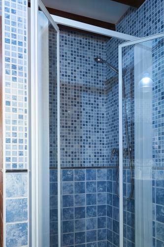 a bathroom with a glass shower with blue tiles at La Escanda in La Rebollada