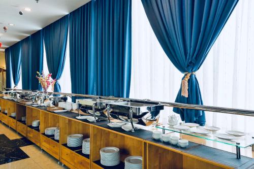 a buffet line with blue curtains and white dishes at Happy Life Hotel District 7 Gần SECC in Ho Chi Minh City