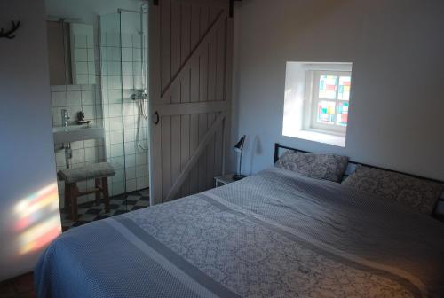een slaapkamer met een bed, een douche en een raam bij WW15 - Het Geitenhuisje in Ruinerwold