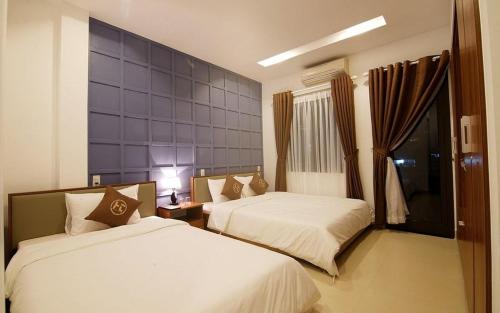 a bedroom with two beds and a blue wall at Poetic Hue Hotel & Spa in Hue
