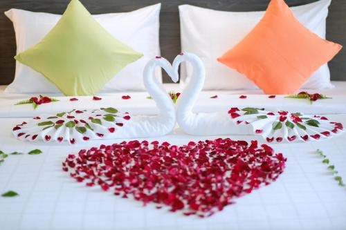 two white swans making a heart on a bed at Clover Hotel Hatyai in Hat Yai