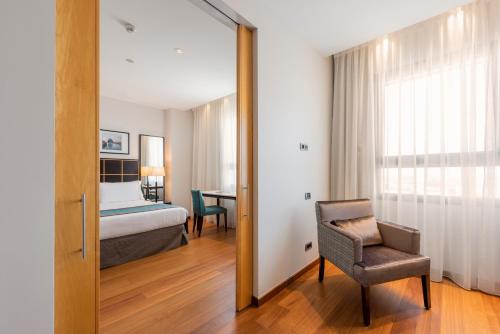 a bedroom with a bed and a chair and a mirror at Eurostars Gran Valencia in Valencia