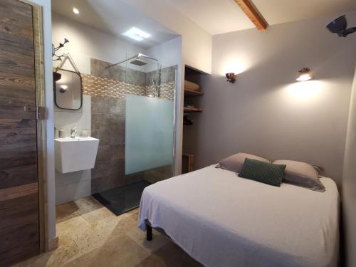 a bedroom with a bed and a bathroom with a sink at Résidence I Levri in Porto-Vecchio