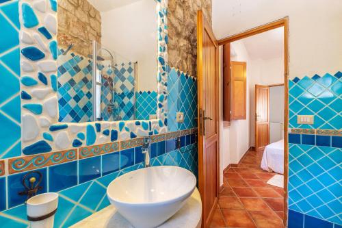 baño con paredes de azulejos azules y lavabo blanco en Casa Bellavista, en Baunei