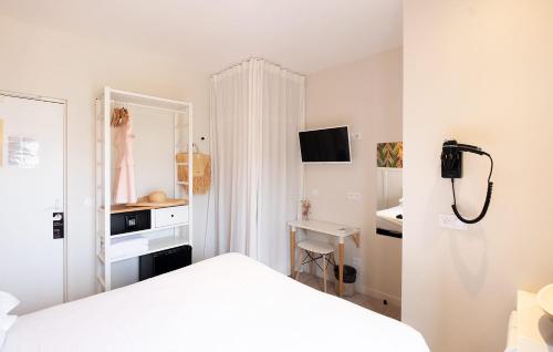 a white bedroom with a bed and a desk at Hôtel de la Plage in Sète