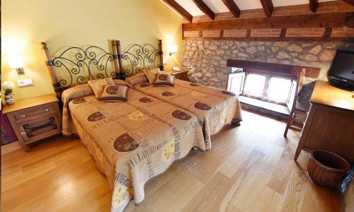 a bedroom with a large bed with a stone wall at Posada Término in Hoznayo