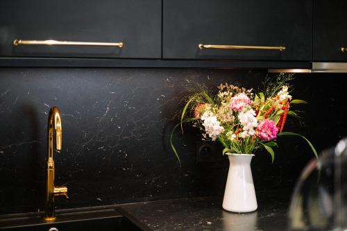 a vase of flowers on a counter next to a sink at Hôtel de la Plage in Sète