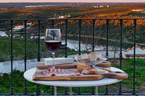a table with a glass of wine and bread and cheese at Casa da Moira in Avis