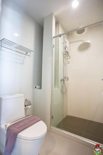 a bathroom with a toilet and a glass shower at Clover Hotel Hatyai in Hat Yai