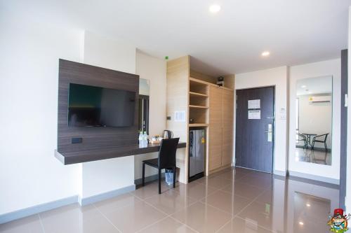 a living room with a desk and a television in a room at Clover Hotel Hatyai in Hat Yai