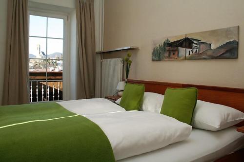 a bedroom with a green and white bed with a window at Gasthof Albergo Kreuzwirt in Völs am Schlern