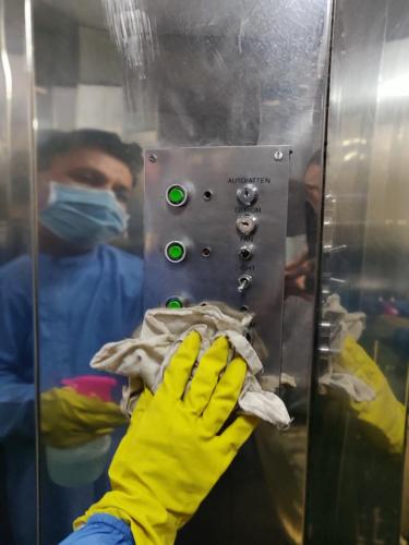 a person wearing a mask and yellow gloves pushing a button in an elevator at Hotel GRG in Vadodara