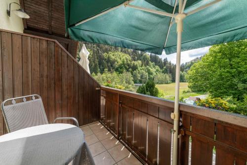 eine Terrasse mit einem Tisch und einem grünen Sonnenschirm in der Unterkunft Haus Wiesenttal in Waischenfeld