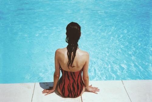 a woman in a swimsuit sitting next to a swimming pool at Waterfront in Sliema