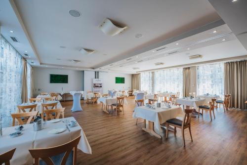 un restaurante con mesas y sillas blancas y una pantalla en Hotel Restaurant Roemer, en Merzig