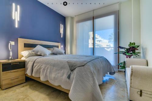 sypialnia z łóżkiem i niebieską ścianą w obiekcie Apartament Delux-La Entrada Punta Prima w mieście Torrevieja