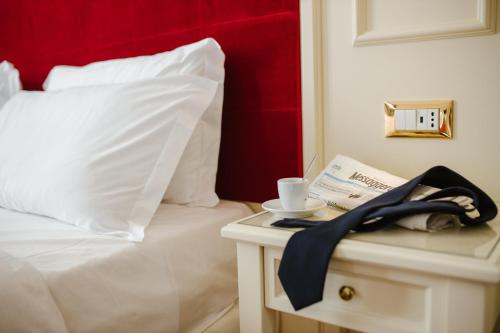 a white bed with a red headboard and a table with a phone at Hotel Città di Parenzo in Trieste