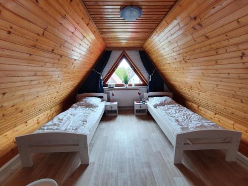 a attic room with two beds and a window at Ferienhäuser Seemannsgarn in Friedrichskoog-Spitz