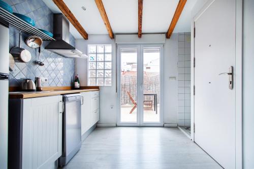 cocina con armarios blancos y puerta abierta en Precioso estudio con terraza privada en la playa, en Valencia