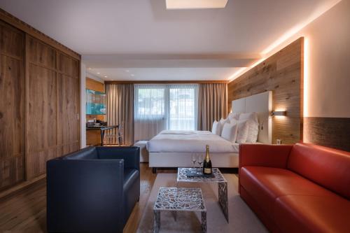 a hotel room with a bed and a couch at Alpinresort ValSaa - Sport & Spa in Saalbach Hinterglemm