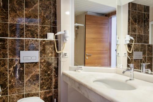 a bathroom with a sink and a toilet and a mirror at Numa Konaktepe Hotel in Konaklı