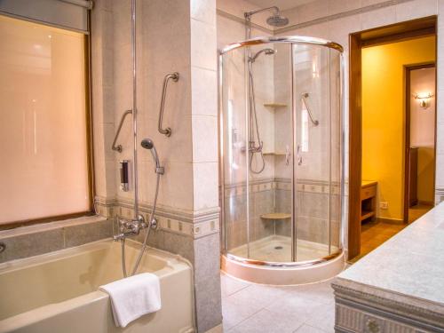 a bathroom with a shower and a tub and a sink at Acron Candolim Regina in Candolim