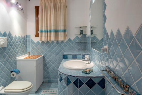 W wyłożonej niebieskimi kafelkami łazience znajduje się umywalka i toaleta. w obiekcie Baragge Hill& Summer Pool w mieście Palau