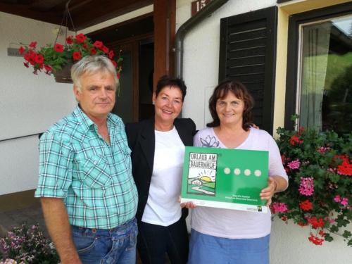 two women and a man holding a sign in front of a house at Bio Bauernhof Moas in Lunz am See