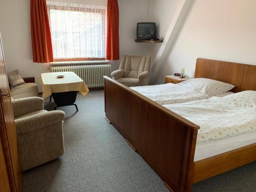 a bedroom with a bed and a chair at Gasthaus Glück auf garni in Häuslingen