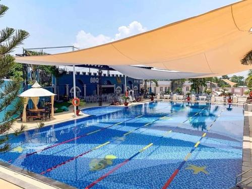 a large swimming pool with a large yellow umbrella at D'Villa Hotel - Homestay in Kon Tum