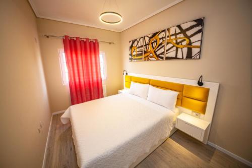 a bedroom with a white bed and a red curtain at Villa Abiori in Ksamil