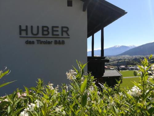 a sign for a huber die tuckler lab with flowers at Huber - Das Tiroler B&B in Oberperfuss