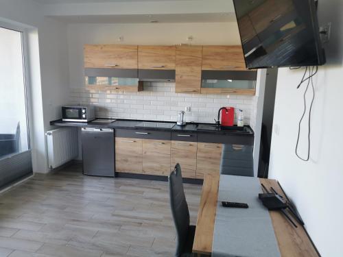 eine Küche mit einem Tisch, einer Spüle und einem Kühlschrank in der Unterkunft Lilla Apartament in Darłówko