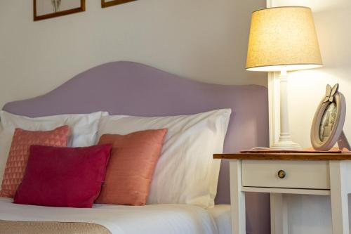 a bed with pillows and a table with a lamp at Residence Ferraud in Pinerolo
