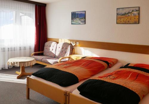 a bedroom with two beds and a chair at Apartments Albana in Saas-Fee