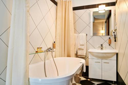 a white bathroom with a tub and a sink at Hotel Phoenix in Zagreb