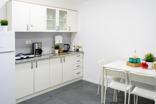 a kitchen with white cabinets and a table and chairs at Kostovski Rooms-near E75 to Greece in Veles