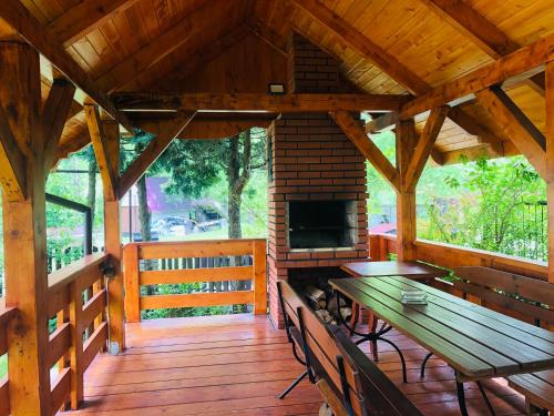a wooden porch with a picnic table and a fireplace at Pensjonat Makuch in Korbielów