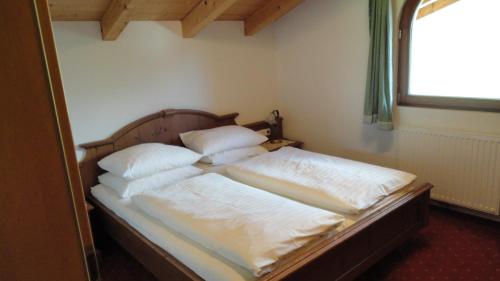 um quarto com uma cama com lençóis brancos e almofadas em Ferienwohnungen Birnbacher em Sankt Ulrich am Pillersee