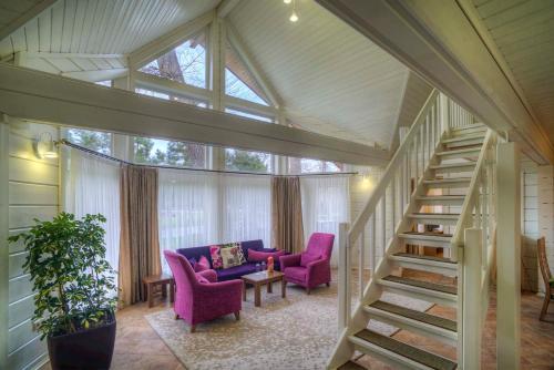 a living room with purple chairs and a staircase at RIVER INN RESORT AND SPA in Nabran