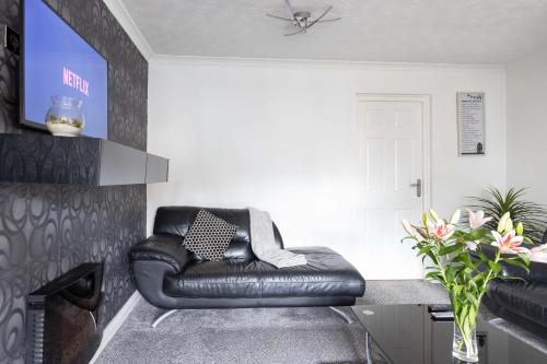 a leather chair in a living room with a fireplace at CAPRI 13 SA - 3 Bedroom House close to Loughborough University, EV car facilities, Free Parking, Free Wifi - Ask for contractor rates! in Loughborough