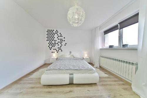 a white bedroom with a bed and a chandelier at Apartament Karpatka in Karpacz